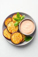 Crispy fried eggplant slices with tahini sauce garnished with fresh herbs create a delightful culinary experience photo