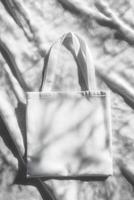 Plain tote bag lying flat on a textured monochromatic surface with soft shadows photo