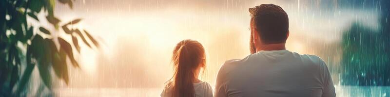 Rainy day blues of a girl and her father watching a summer thunderstorm from the window photo