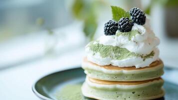 A stack of pancakes topped with whipped cream and blackberries photo