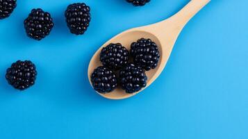 Blackberries on a wooden spoon on a blue background photo