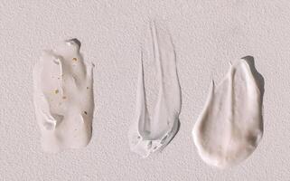 Different texture of gel and cream on a light background. Transparent serum with bubbles and colloidal gold. photo