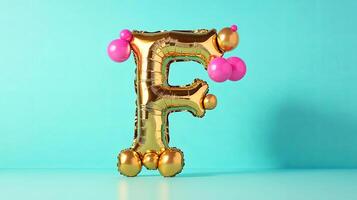 Golden balloon letter F, adorned with colorful pink accents, stands against a vibrant turquoise background, creating a playful and festive atmosphere for celebrations and events photo