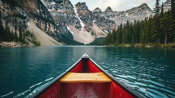 Canoe gliding through tranquil blue lake surrounded by majestic mountains and lush green trees, capturing serene nature and outdoor adventure experience photo