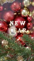 Christmas flatley with New Year lettering on blurred red gold background baubles decoration. Close-up, shiny composition. Postcard . Vertical photo