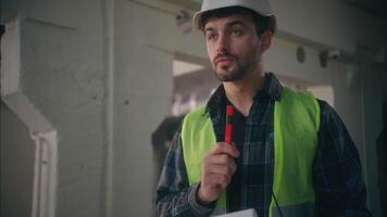 Thoughtful Caucasian builder man planning paper notepad working in construction male in hardhat handyman think supervisor contractor writing puzzled guy foreman planning build industrial work control video