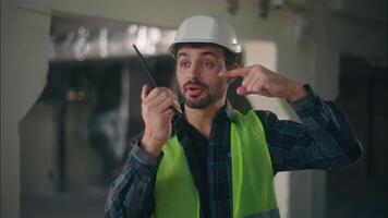 Caucasian builder talk man pointing on walkie talkie in construction electrician contractor male gesturing check radio set sign tech connection guy engineer supervisor communicate building inspection video