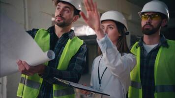 Three Caucasian builders woman men teamwork building talk in construction controllers architects engineers contractors colleagues inspecting architectural project industry radio set draft cooperation video
