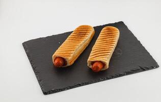 Grilled hot dogs in toasted buns on a sleek serving board photo