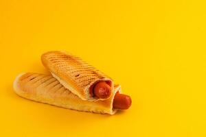 Hot dog wrapped in toasted bread on bright yellow background photo