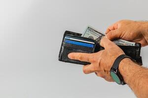 Hands taking cash from a black wallet against a light background photo