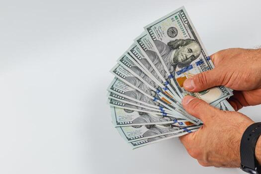 Man counting stack of hundred dollar bills on a plain background photo