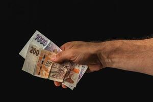 Hand holding various banknotes against dark background photo