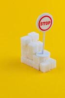 Sugar cubes stacked with a stop sign on a bright yellow backdrop photo
