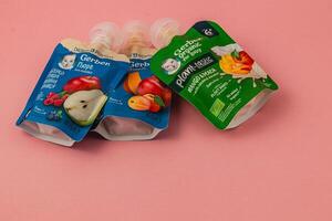 Lviv Ukraine 05.06.25 Organic baby food pouches arranged on a pink background photo