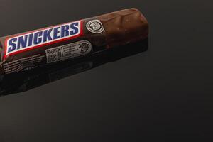 Lviv Ukraine 05.06.25 Chocolate bar on a reflective surface in a dim light setting photo