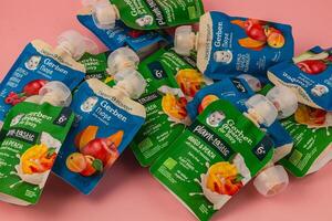 Lviv Ukraine 05.06.25 Variety of baby food pouches arranged on a pink background photo