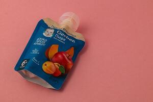 Lviv Ukraine 05.06.25 Organic fruit puree pouch for babies on pink background photo