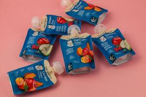 Lviv Ukraine 05.06.25 Fruit puree pouches in various flavors on pink background photo