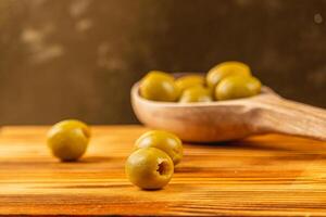 Fresh green olives on a wooden surface with a rustic setting photo