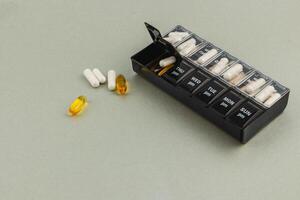 Weekly pill organizer with various medications on a gray surface photo