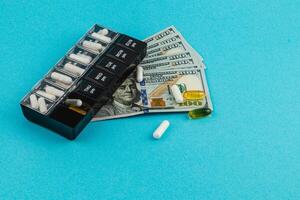 Medication organizer beside cash on blue surface photo