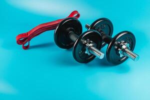Dumbbells with a resistance band on a bright blue background photo