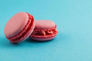 Delicate pink macarons on bright turquoise background photo