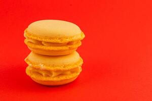Delicious yellow macarons stacked on a vibrant red background photo