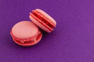 Pink macarons arranged on a vibrant purple background photo
