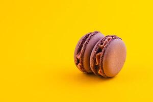 Chocolate macarons on vibrant yellow background photo