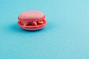 Delicate pink macaroon on a vibrant blue background photo