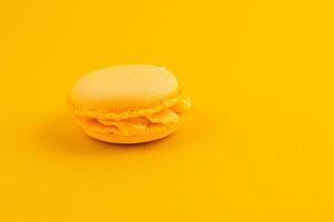 Bright yellow macaroon sits on vibrant yellow background photo