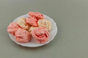 Soft meringues in pink and cream shades on white plate photo