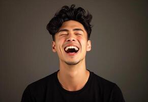 Portrait of a joyful young man laughing with expressive facial features and a dark background photo
