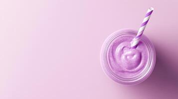 glass jar with a violet and white striped straw. The jar is filled with a purple smoothie or milkshake. The background is a light purple color. photo