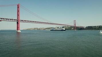 Lisbon, Portugal, 2025 - The ship sails under a red suspension bridge on a wide river in Portugal. Yachts and sailboats sail on the river. Drone . - Yachts photo