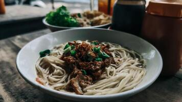 A Bowl of Savory Cwie Mie Topped with Chicken photo