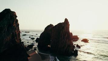 Sharp peaks of rocks on the seashore washed by sea waves. Drone at sunset photo