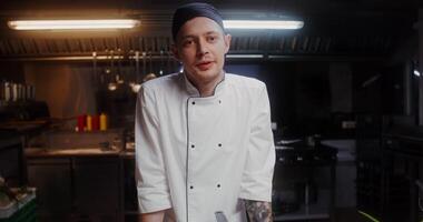 A man in a chef's uniform speaks and shows the products standing near the frying pan in the kitchen of the restaurant photo