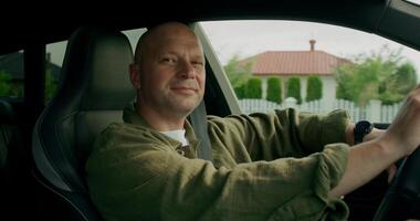 The man is driving the car, he is wearing a seat belt. Front view. Summer day photo