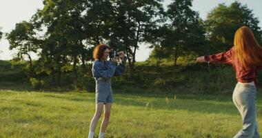 Two young women are filming a on camera standing in a field on a sunny summer day. photo