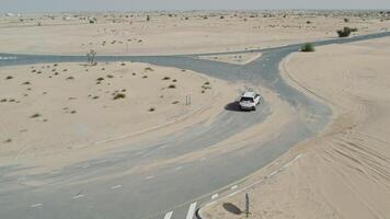 The car is driving along the ring road among the sand dunes in the desert. Drone view while driving photo