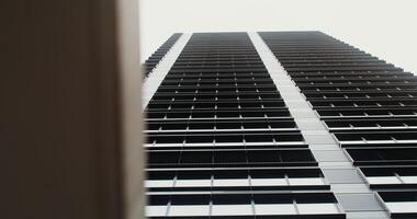 Facade of a high-rise office building with large panoramic windows. Business Quarter, no people on . The gray building of the business center. Skyscraper, view from below. in 4k, red komodo photo