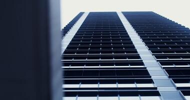 Facade of a high-rise office building with large panoramic windows. Business Quarter, no people on . The gray building of the business center. Skyscraper, view from below. photo