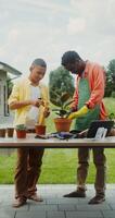 A father in an apron and rubber gloves teaches his son to take care of pot flowers standing in the backyard of their house - gloves photo
