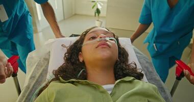Medics are taking a woman on a gurney along the hospital corridor. The oxygen tube is in her nose photo