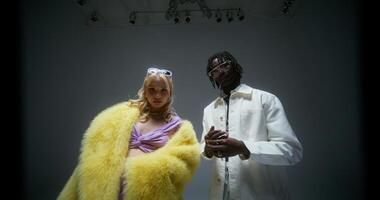 Glamorous men and a woman look at the camera with serious look. Photo shoot in the studio