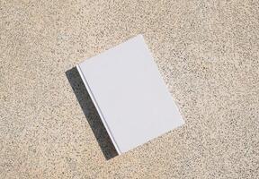 empty white book mockup on concrete stone floor or pavement outdoors photo