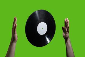 A vinyl record elegantly floating between two hands against a vibrant green background photo